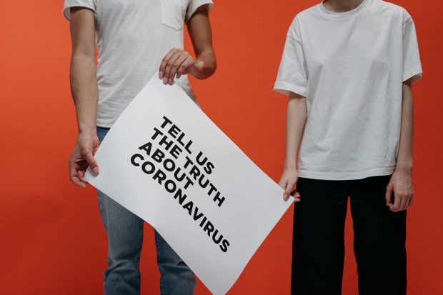 People holding a sign asking the truth about the coronavirus. 