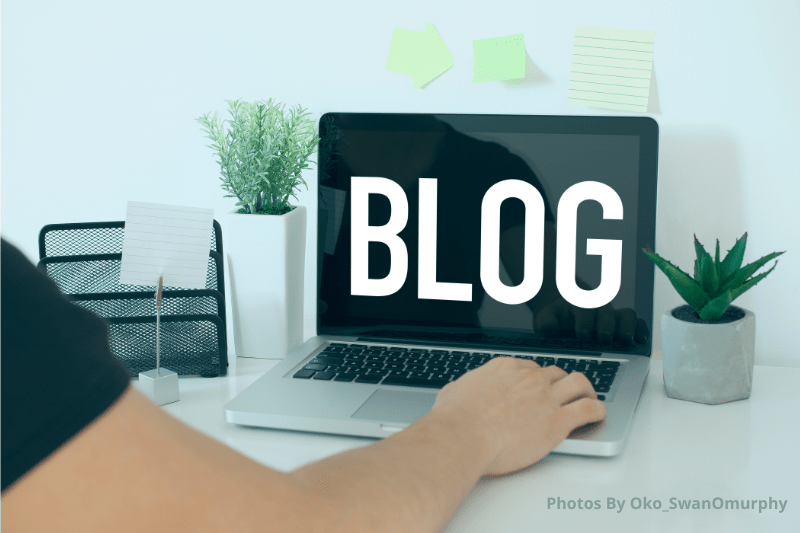 "Blog" on a laptop screen in large white letters on a black background. One hand resting on the keyboard. 