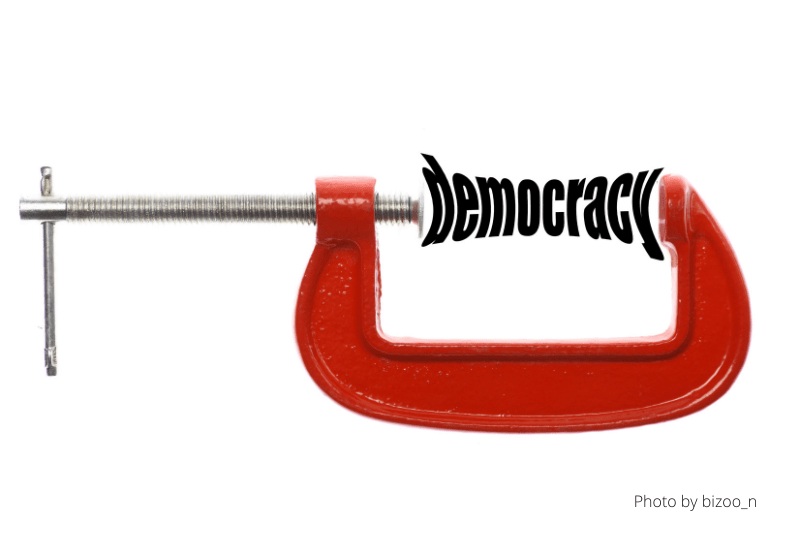 Democracy squeezed in red C-clamp