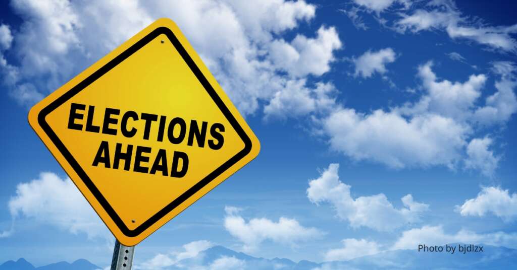 Elections Ahead sign with a partly cloudy background.