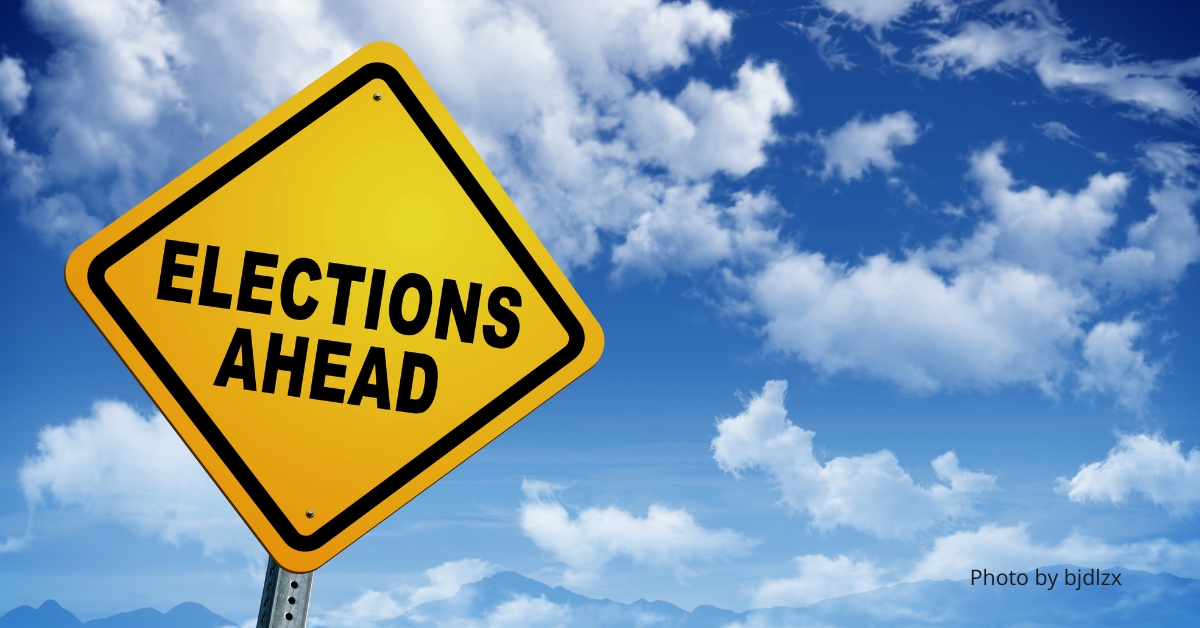 Elections Ahead sign with a partly cloudy background.