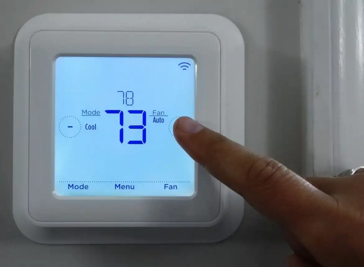 Finger adjusting Smart Thermostat to a higher temperature. It highlights the cost to lower income people of Stuebe's vote to repeal HEHRP.